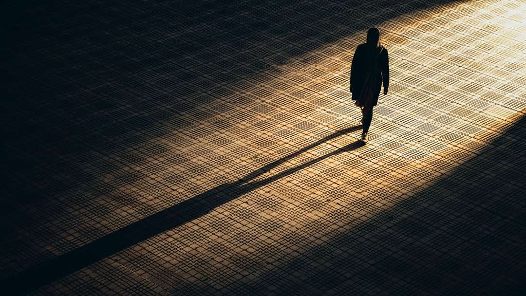 мъж в черно яке, ходещ по кафяв тухлен под онлайн пъзел