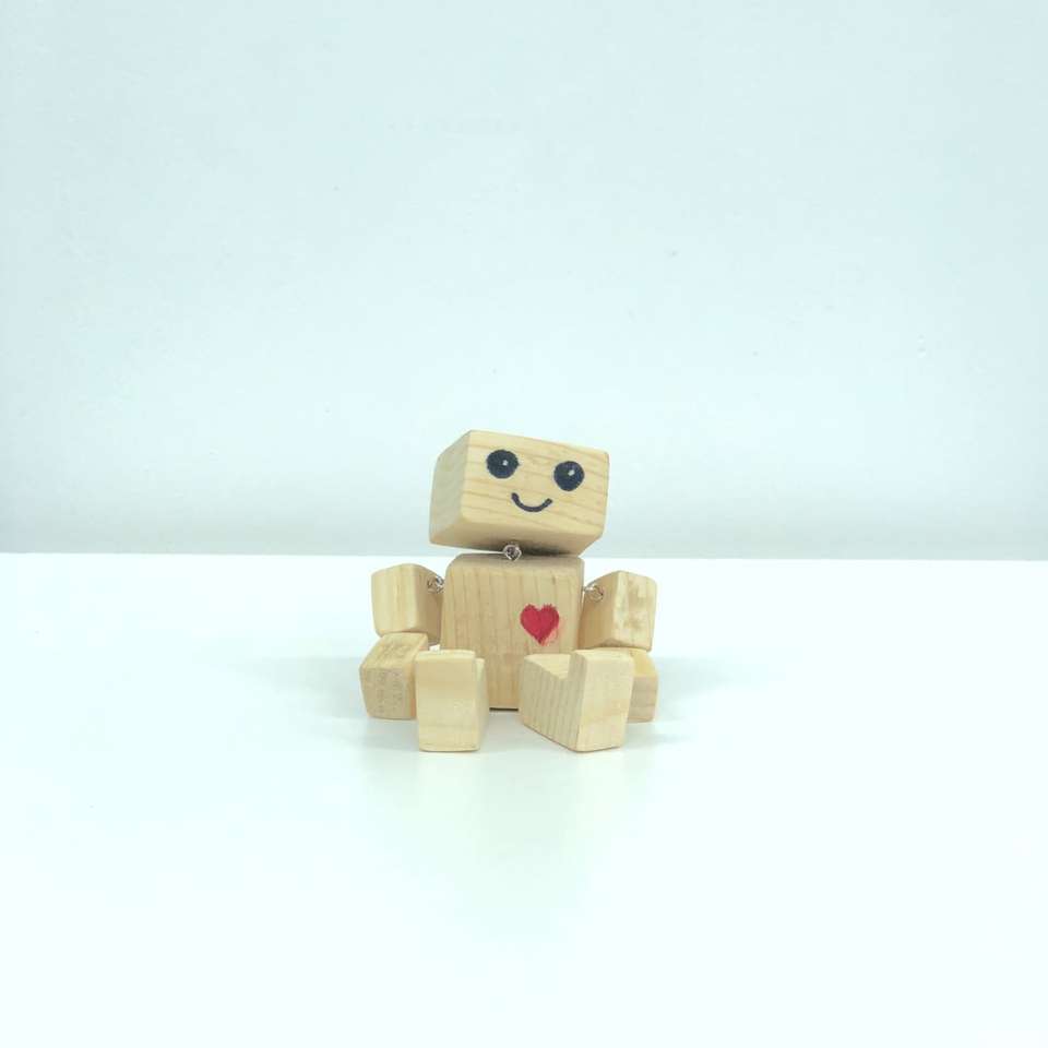 Juguete robot de madera marrón sobre superficie blanca rompecabezas en línea