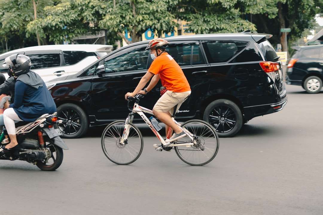 Hombre en camiseta naranja montando en bicicleta blanca rompecabezas en línea