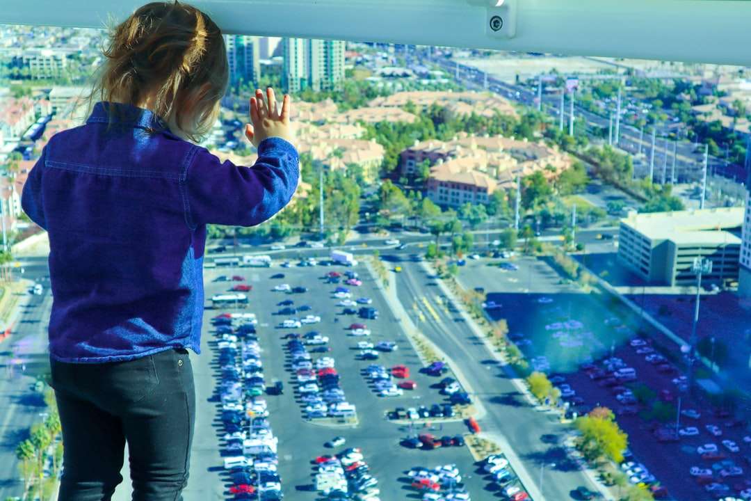 κορίτσι σε μπλε σακάκι στέκεται πάνω από το κτίριο ψάχνει online παζλ