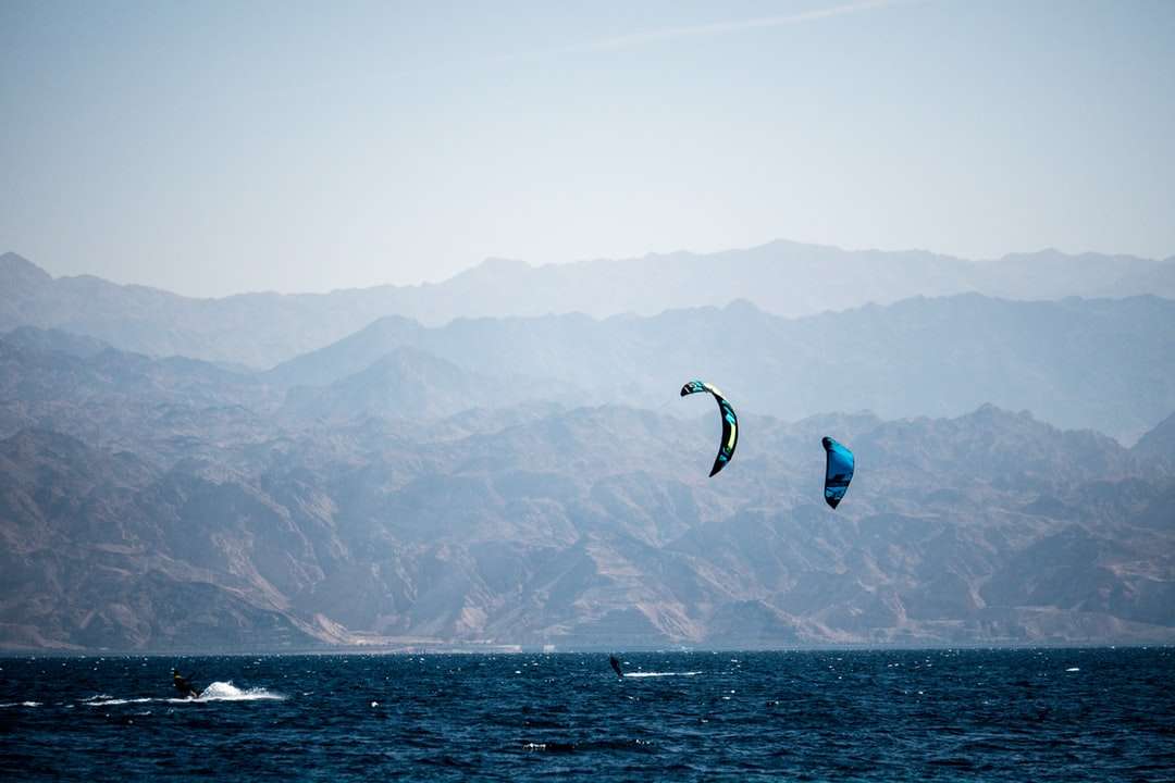 човек в сини и бели шорти, сърфиращ по море онлайн пъзел