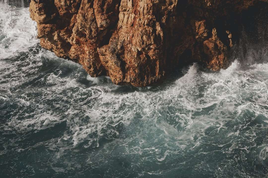 montagna rocciosa marrone accanto al corpo d'acqua durante il giorno puzzle online
