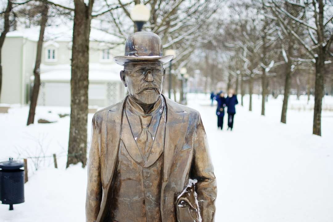 Hombre en estatua de abrigo de cuero marrón durante el día rompecabezas en línea