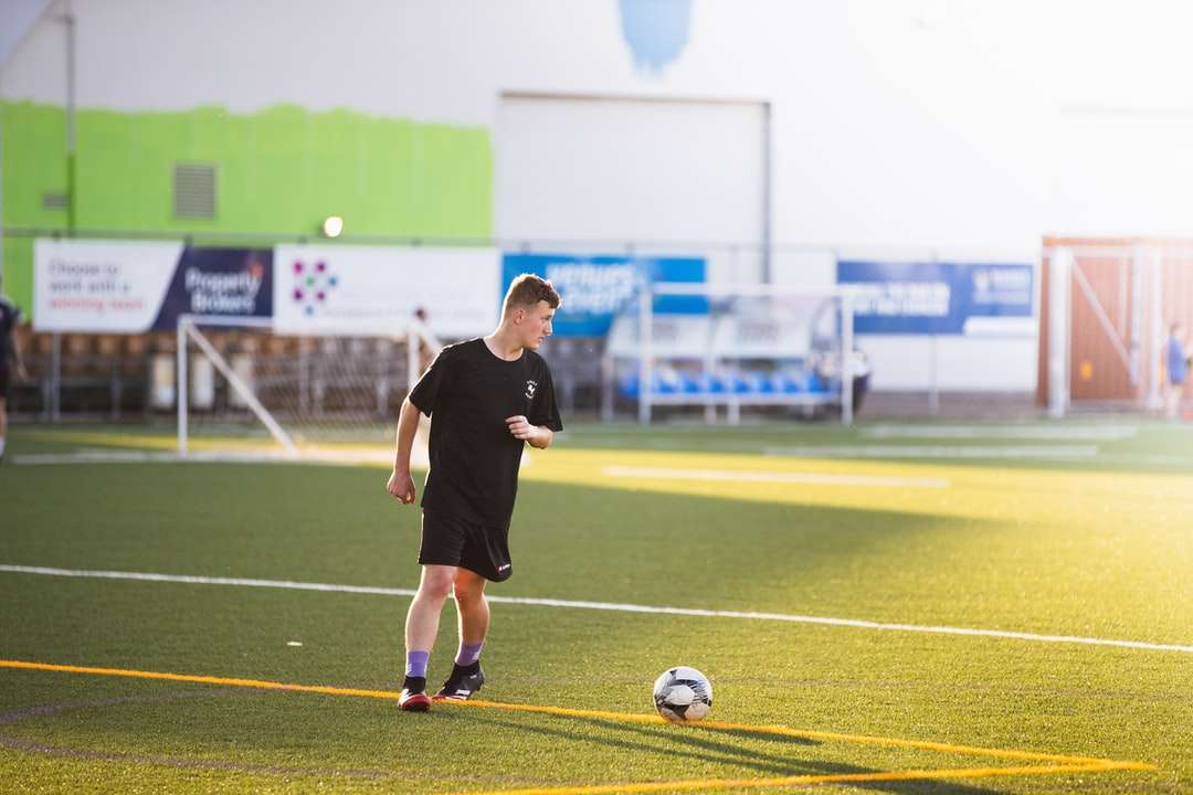 мъж в черна риза и къси панталони, играещ футбол през деня онлайн пъзел