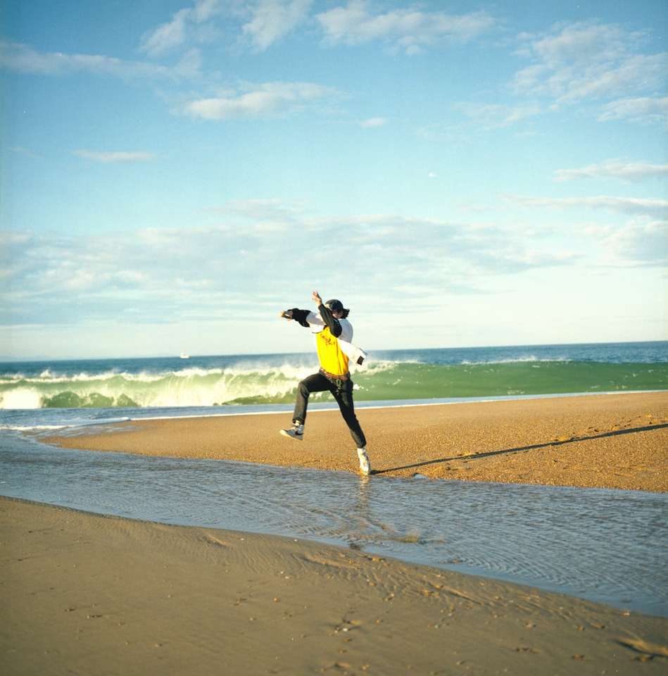 Femme en veste noire et jupe jaune debout sur le bord de mer puzzle en ligne