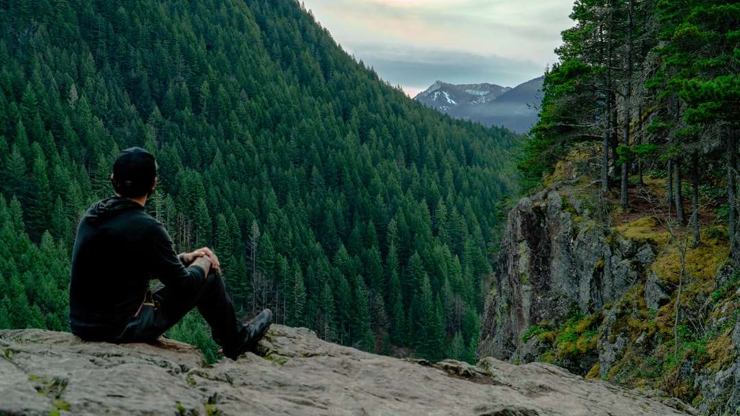 岩の上に座っている黒いジャケットと黒いズボンの男 ジグソーパズルオンライン