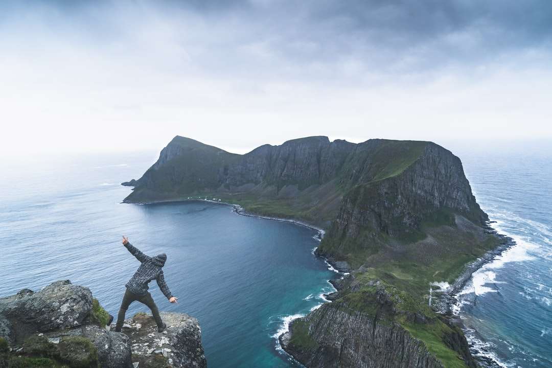 muž v černé košili sedí na skalní útvar poblíž těla online puzzle
