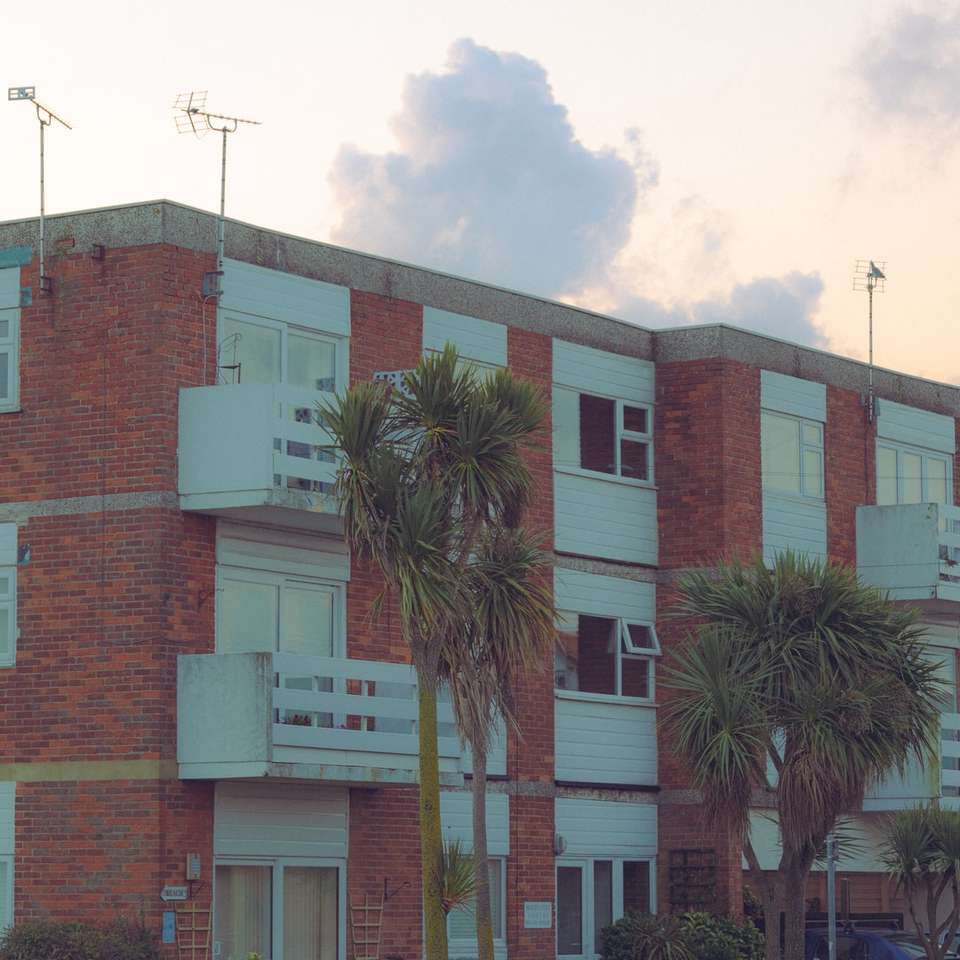 edifício de concreto marrom e branco perto de palmeiras quebra-cabeças online