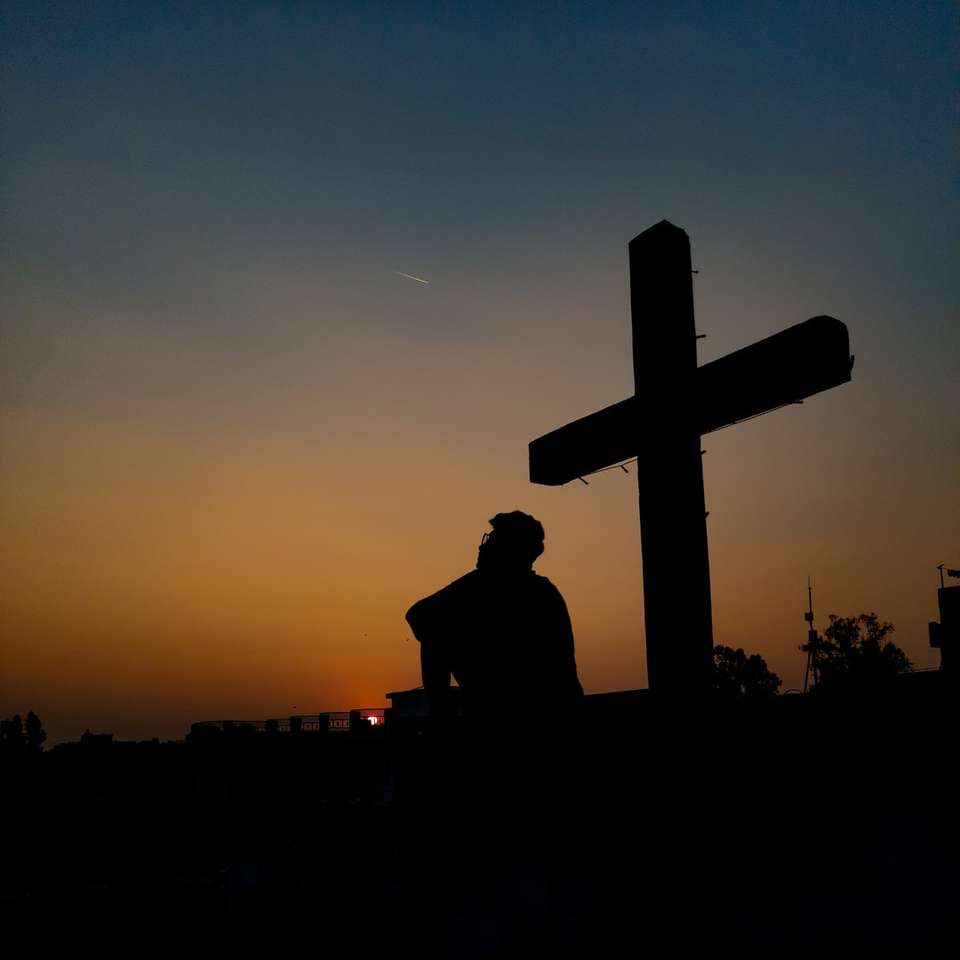 силует людини, що стоїть біля хреста під час заходу сонця пазл онлайн