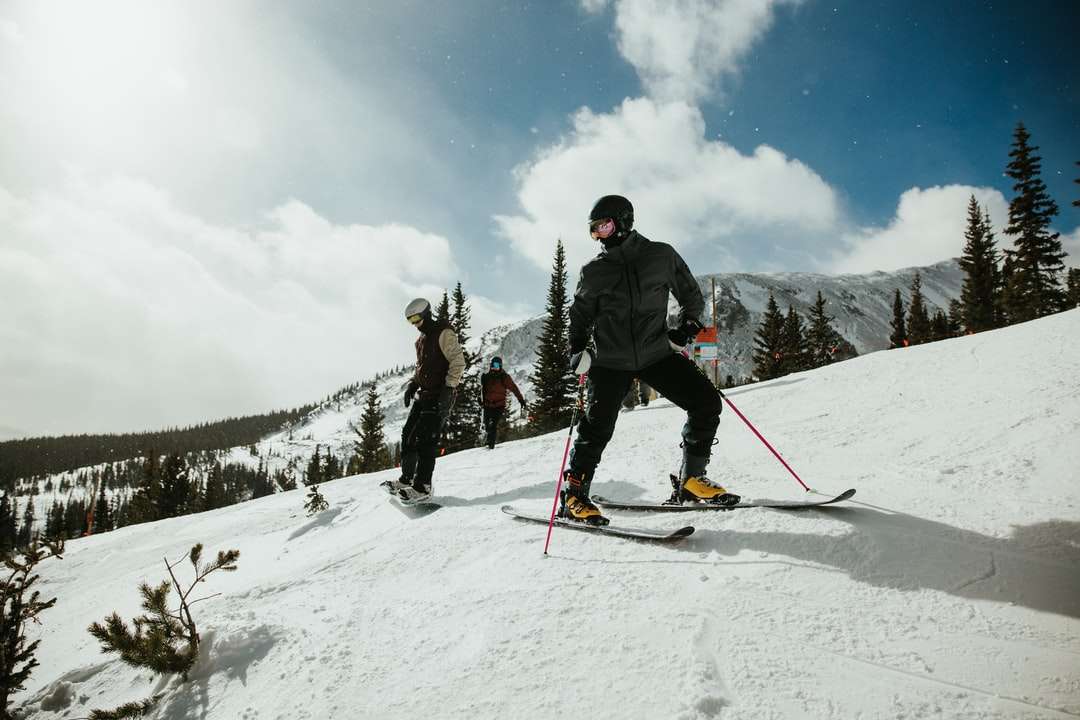 Hombre de chaqueta negra y pantalón azul cabalgando sobre palas de esquí rompecabezas en línea