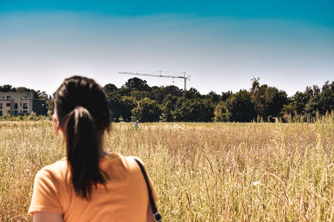 жена в жълт потник, стоящ на поле с кафява трева онлайн пъзел