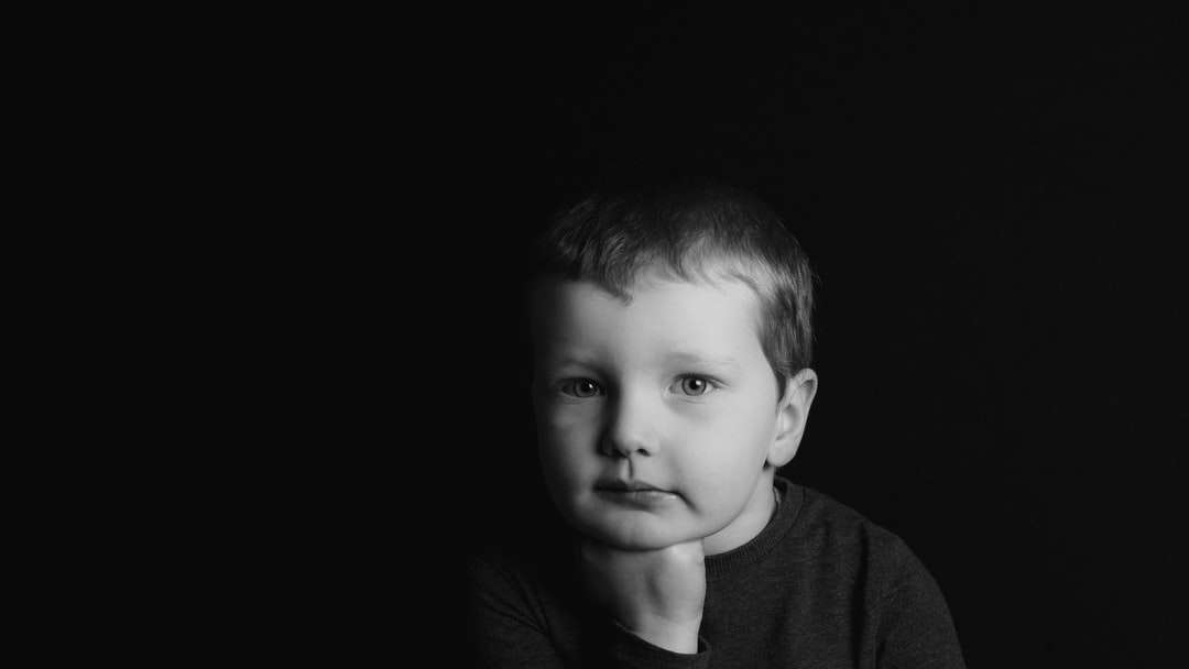 Foto en escala de grises del niño con camisa de cuello redondo rompecabezas en línea