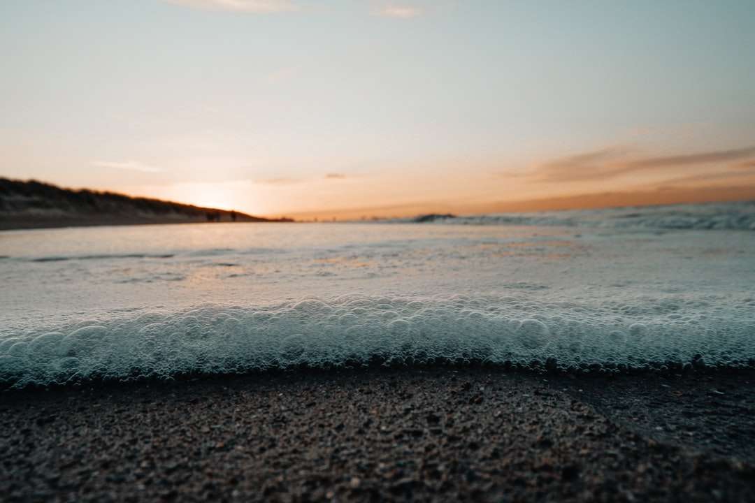Olas del océano rompiendo en la orilla durante la puesta de sol rompecabezas en línea