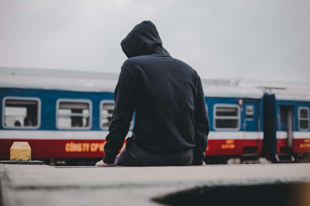 мъж в черна качулка, стояща близо до бял и червен влак онлайн пъзел