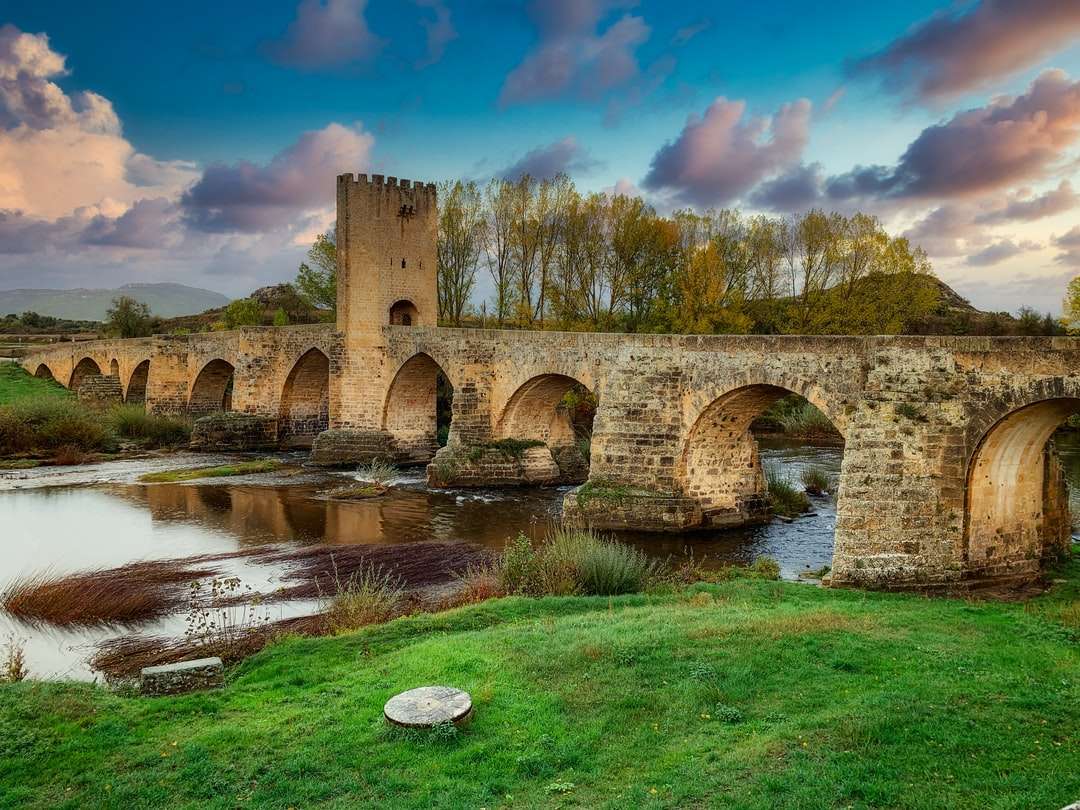 braune Betonbrücke über Fluss unter blauem Himmel Puzzlespiel online
