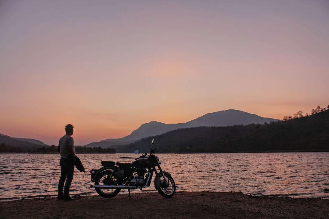 чоловік і жінка, стоячи біля мотоцикла біля водойми пазл онлайн