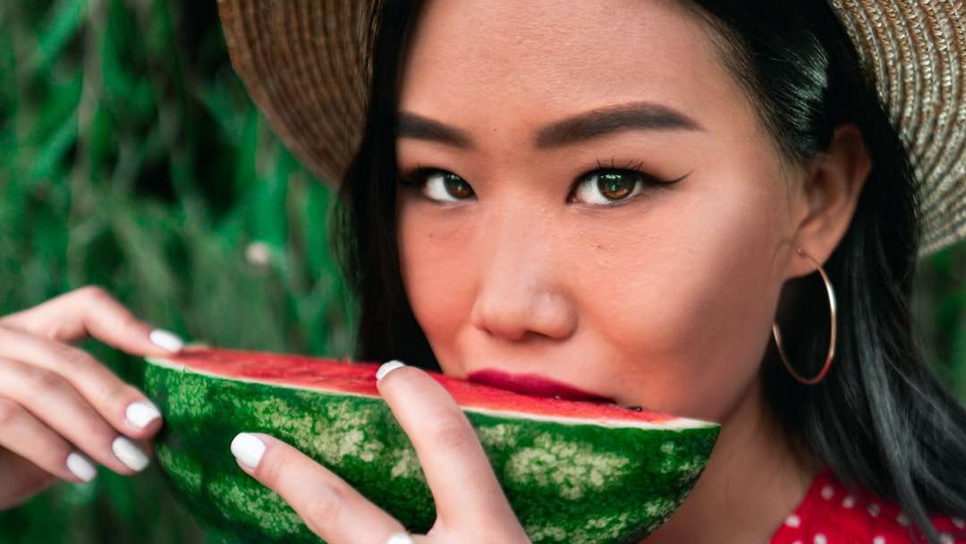 Frau im braunen Sonnenhut, der geschnittene Wassermelone hält Online-Puzzle