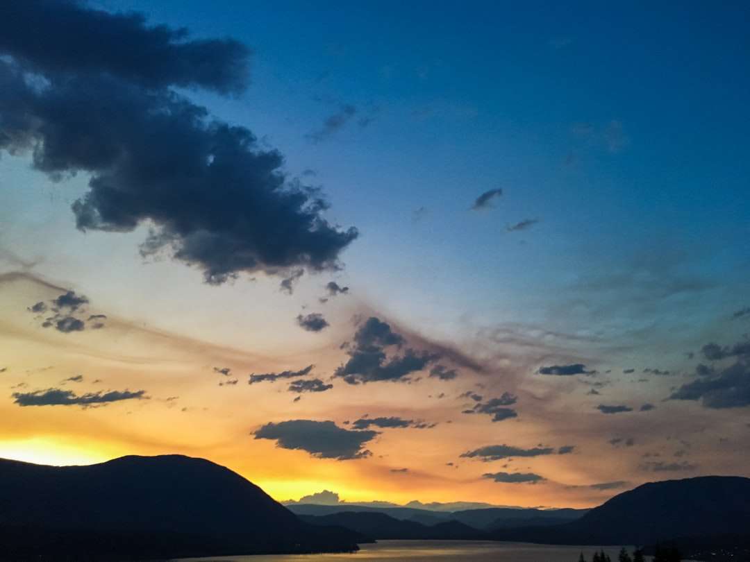 silhueta da montanha sob o céu azul durante o pôr do sol quebra-cabeças online