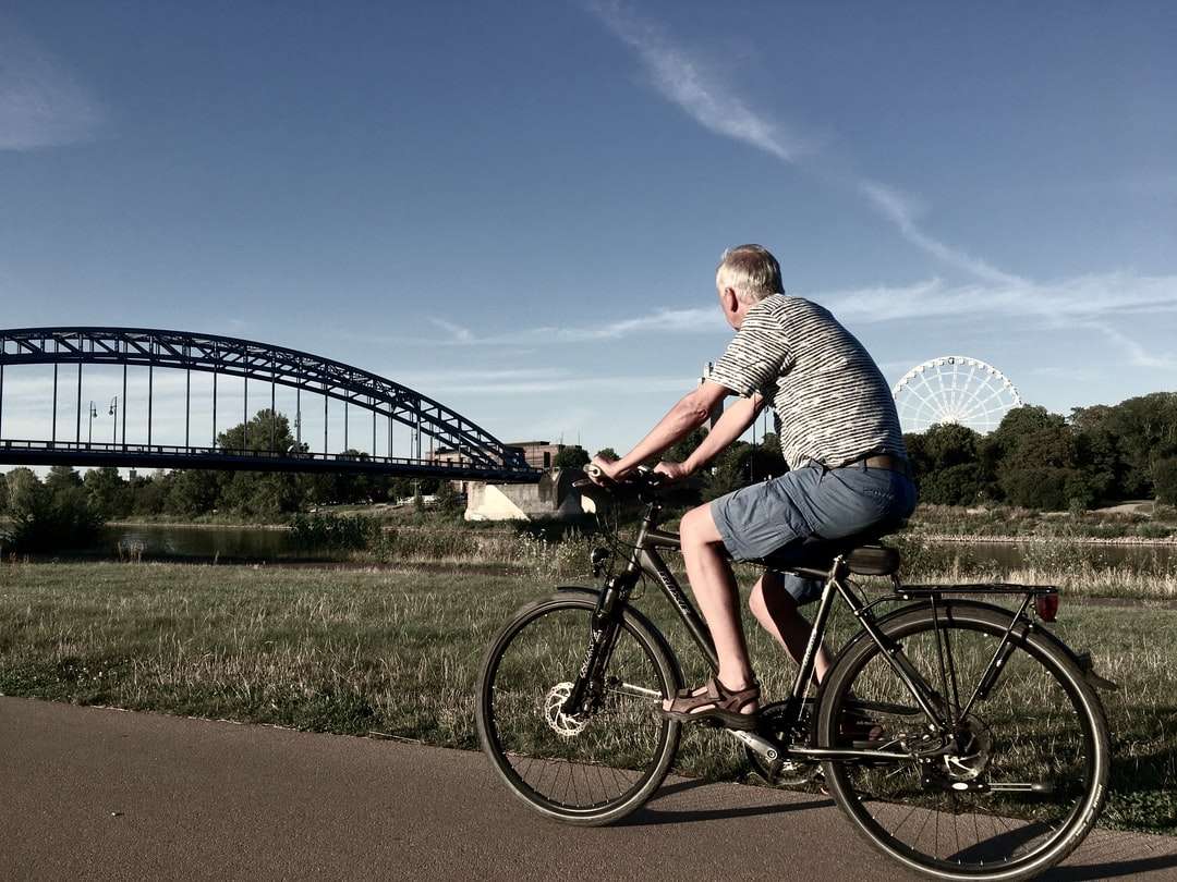 Hombre con camisa a rayas gris y blanca montando bicicleta negra rompecabezas en línea