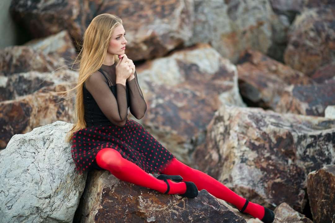 nő fekete ujjatlan ruhában ül a szürke szikla kirakós online