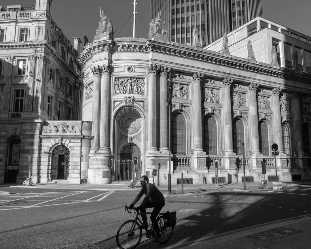 grijswaardenfoto van man fietsten op weg in de buurt van gebouw legpuzzel online