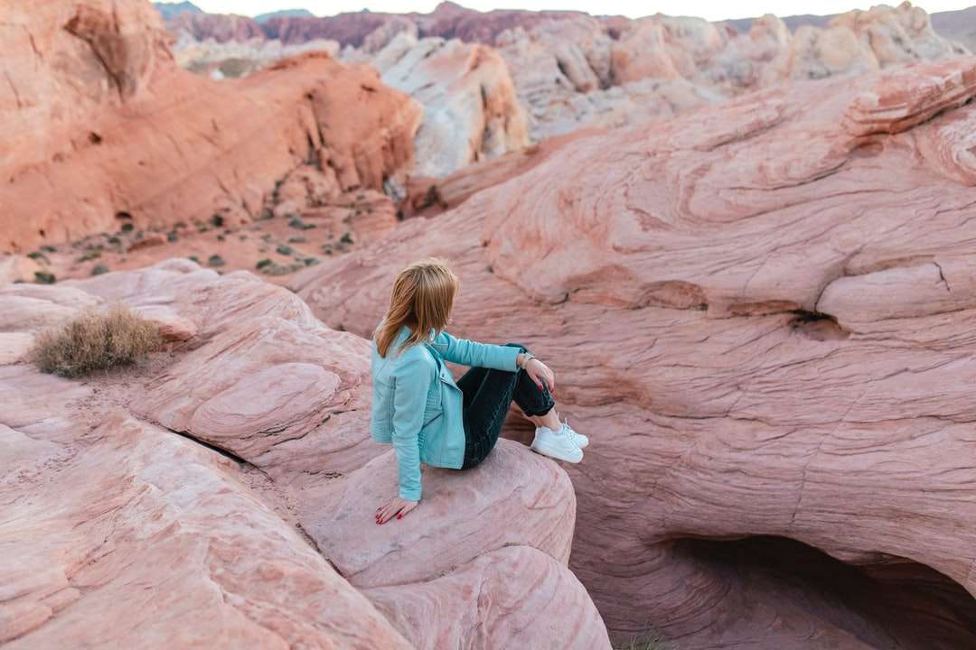 donna in giacca blu seduto sulla formazione rocciosa marrone puzzle online