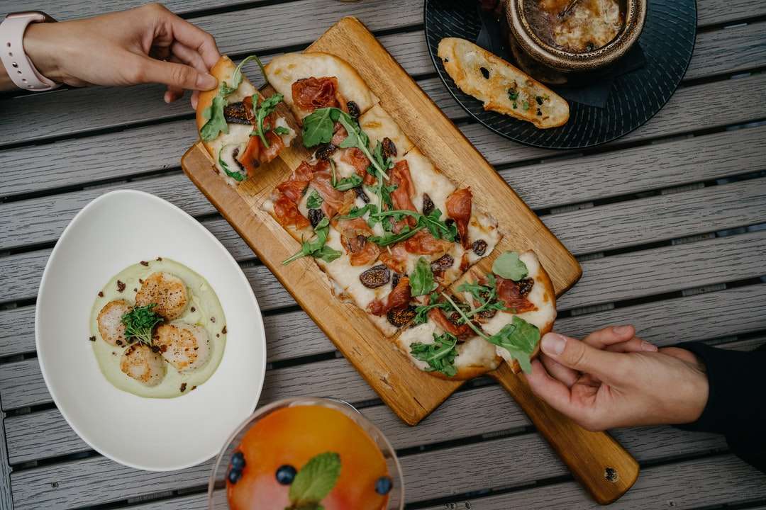 нарезанная пицца на коричневой деревянной разделочной доске пазл онлайн