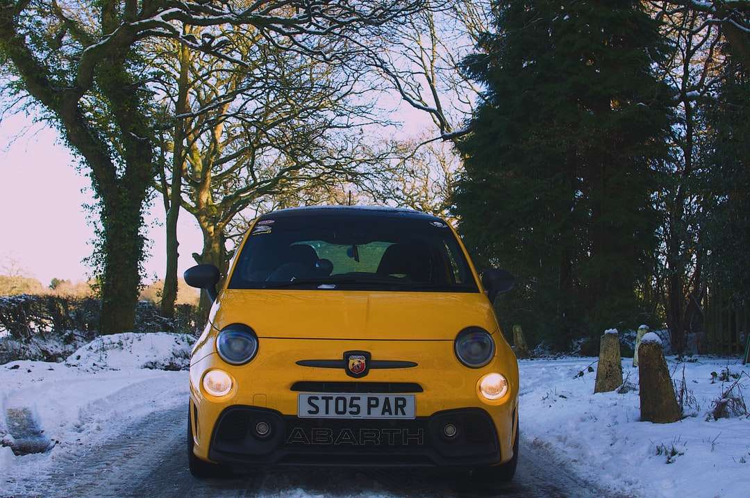 Mini Cooper amarillo y negro estacionado en un terreno cubierto de nieve rompecabezas en línea