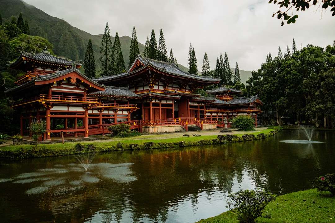 templo marrom e preto perto do lago e árvores verdes puzzle online