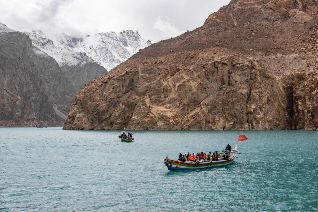 pessoas andando de barco no mar perto da montanha durante o dia quebra-cabeças online