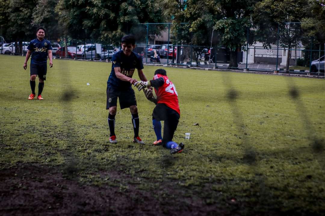 2 băieți care joacă fotbal pe teren cu iarbă verde în timpul zilei puzzle online