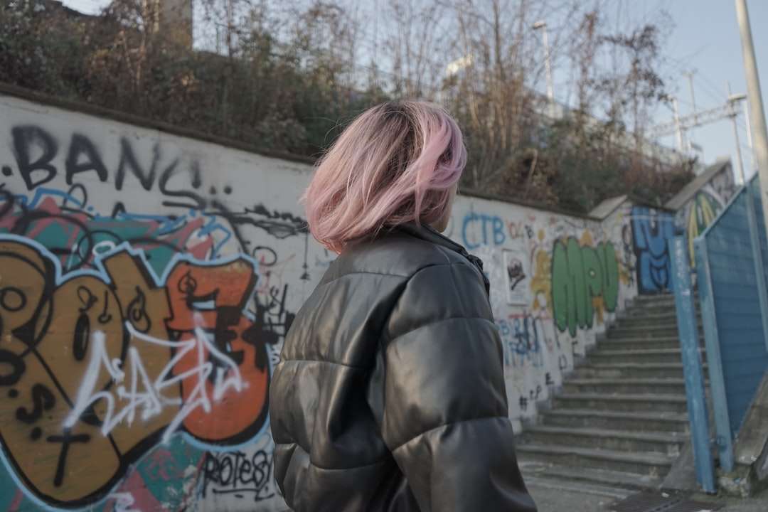 Frau in der schwarzen Jacke, die nahe Graffitiwand steht Online-Puzzle