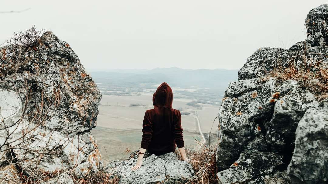 vrouw in bruine hoodie zittend op rotsformatie online puzzel