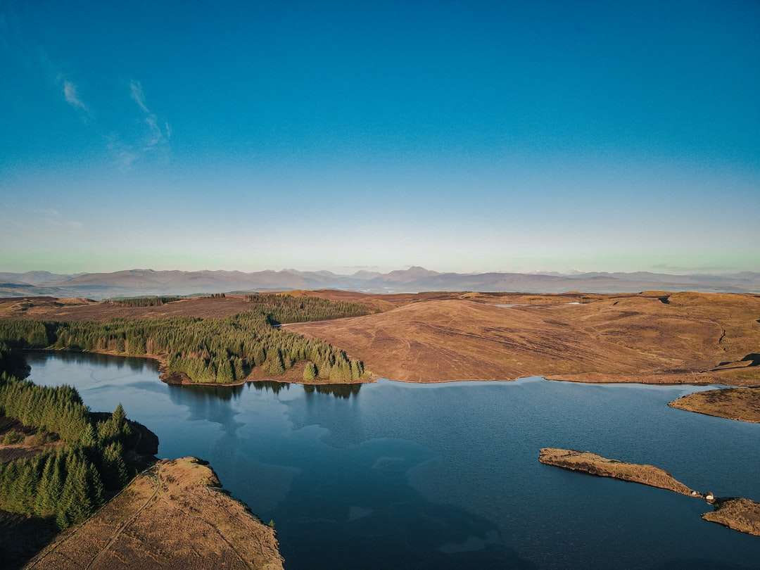 кафяви планини близо до езерото под синьо небе през деня онлайн пъзел