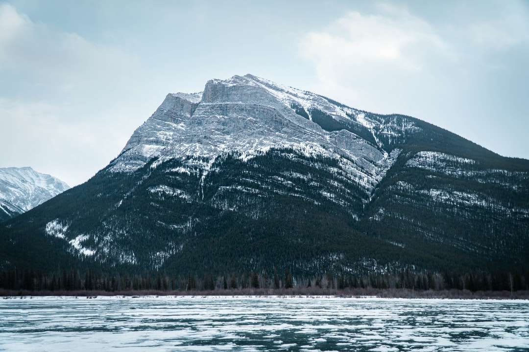 montanha coberta de neve perto do corpo d'água durante o dia quebra-cabeças online