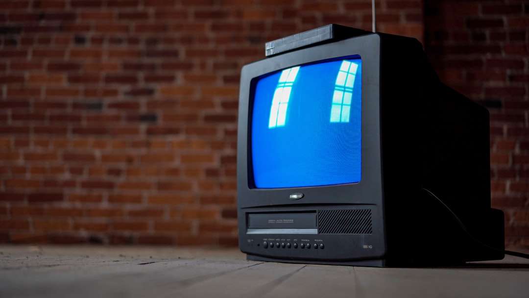Серый ЭЛТ-телевизор включен рядом с коричневой кирпичной стеной пазл онлайн
