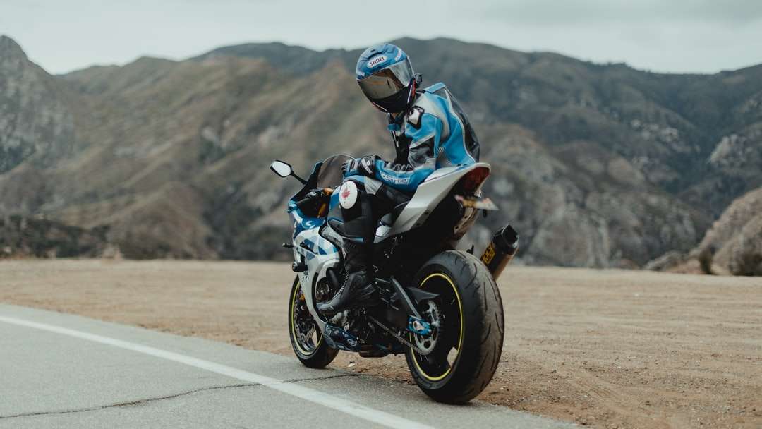 Hombre de chaqueta azul y blanca montando motocicleta negra rompecabezas en línea