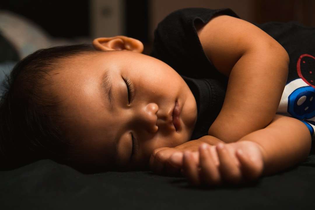 бебе в черен потник, лежащо върху черен текстил онлайн пъзел