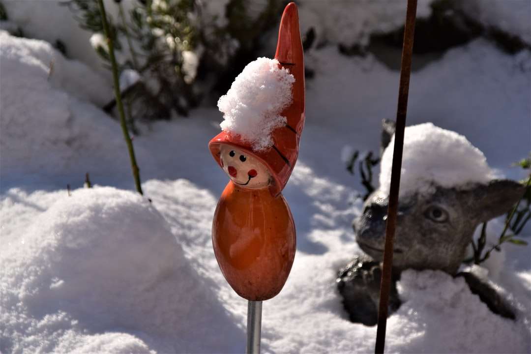 πορτοκαλί ειδώλιο πουλιών σε χιονισμένο έδαφος παζλ online