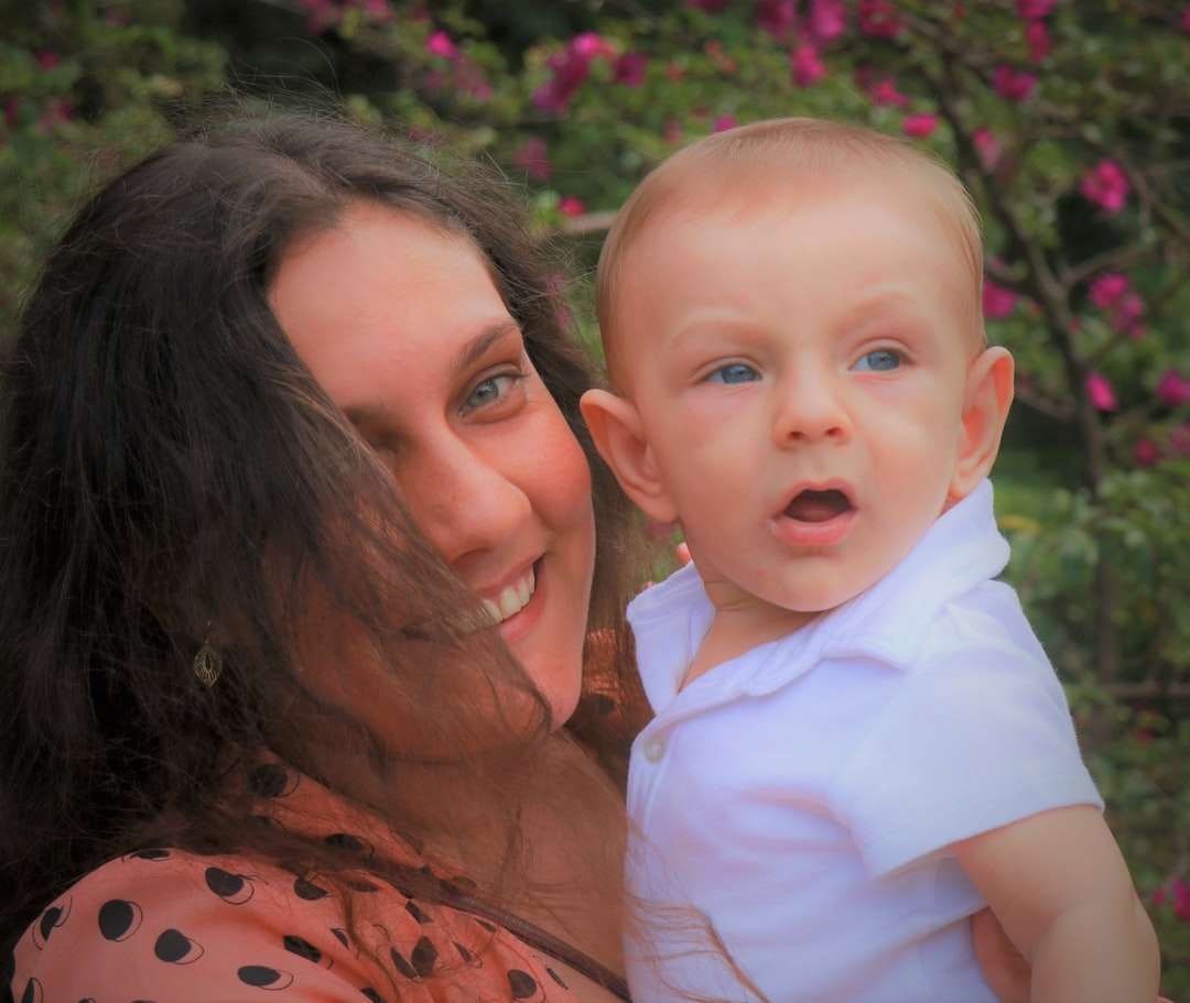 Frau im orangefarbenen und schwarzen Hemd, das Baby im weißen Hemd trägt Puzzlespiel online