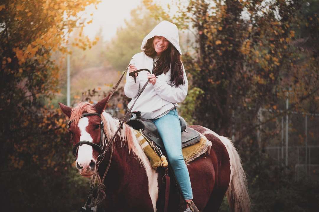 Mujer en camisa blanca de manga larga montando caballo marrón rompecabezas en línea