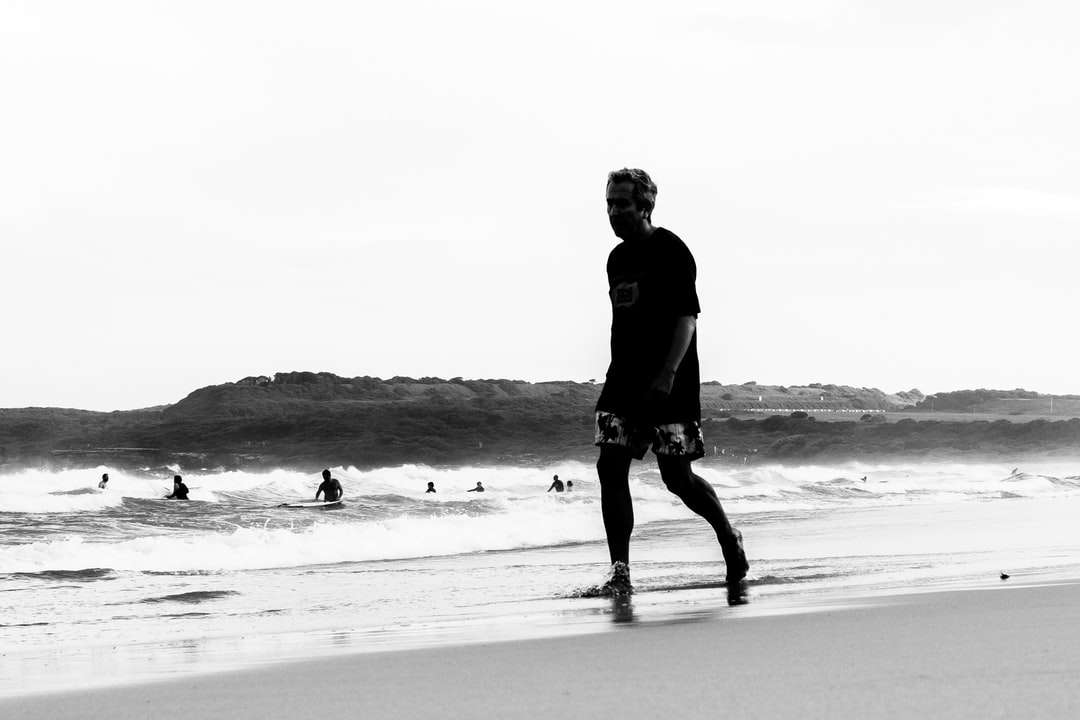 Hombre de chaqueta negra caminando en la playa rompecabezas en línea