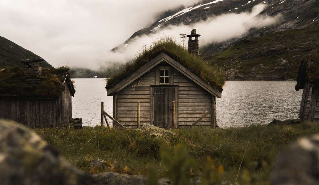 hnědý dřevěný dům na zelené louky poblíž vodní plochy skládačky online