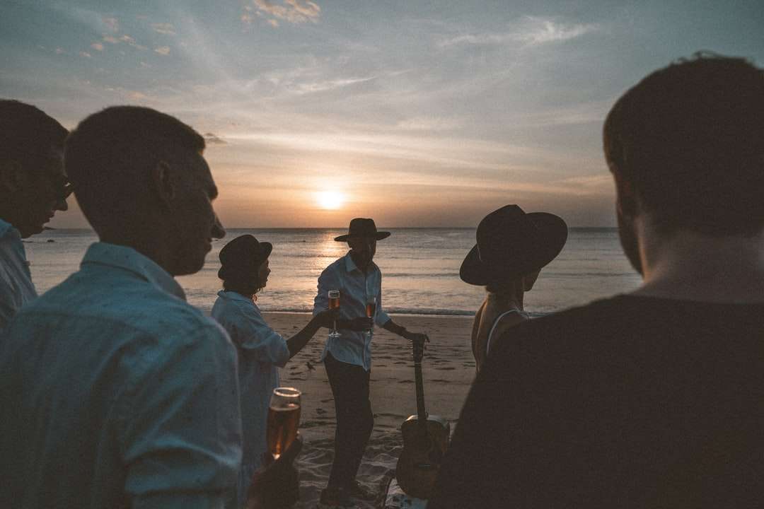 Schattenbild der Leute, die während des Sonnenuntergangs an der Küste stehen Puzzlespiel online