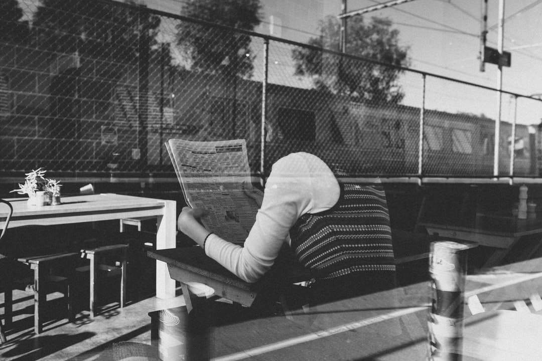 Persona con camisa blanca de manga larga sentada en un banco rompecabezas en línea