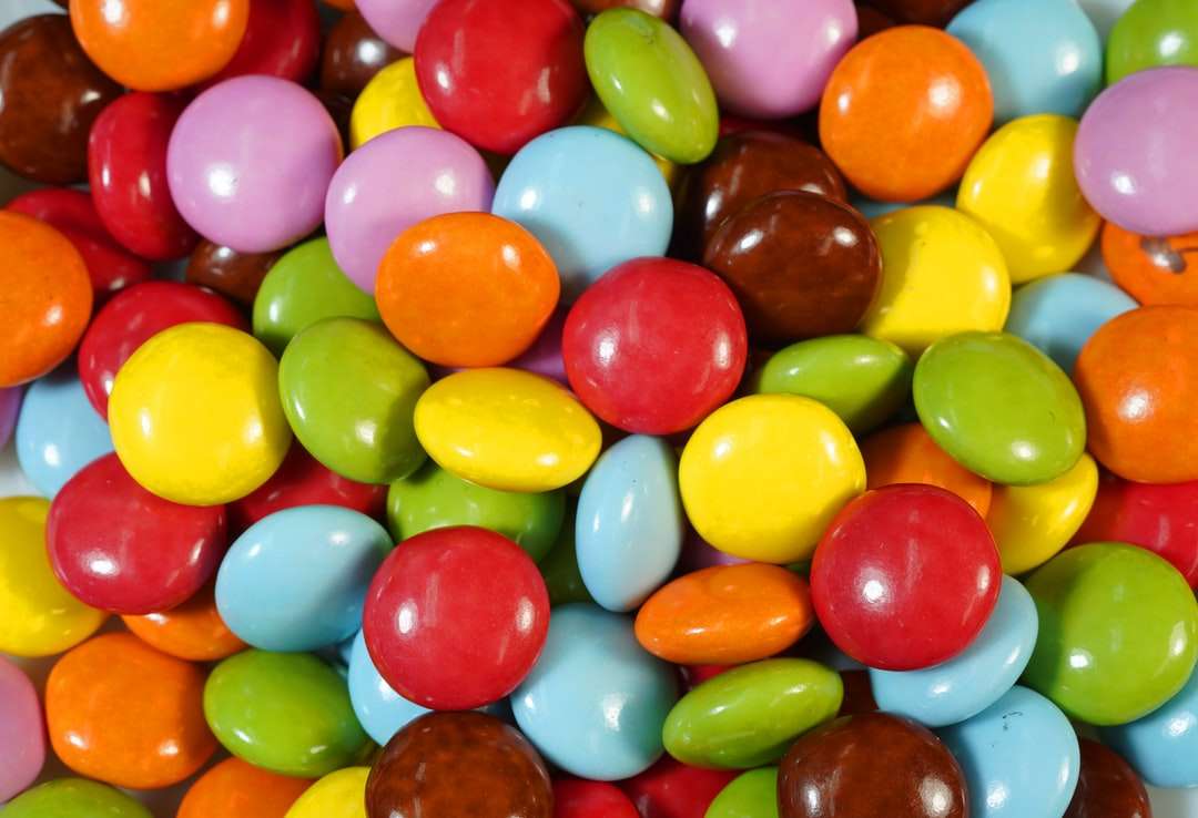 конфеты разных цветов на коричневом деревянном столе пазл онлайн