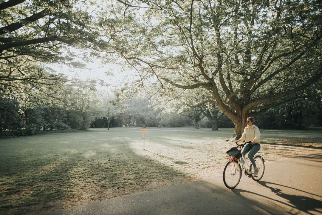 мъж в черно яке, каращ велосипед по пътя през деня онлайн пъзел