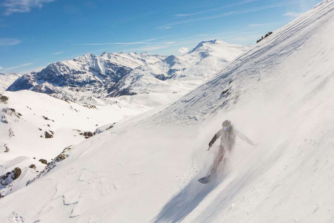 Persona caminando sobre montañas cubiertas de nieve durante el día rompecabezas en línea