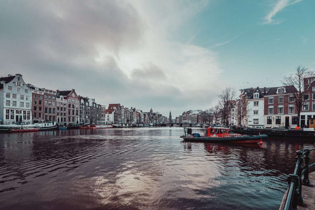 червена лодка на водно тяло в близост до градските сгради през деня онлайн пъзел