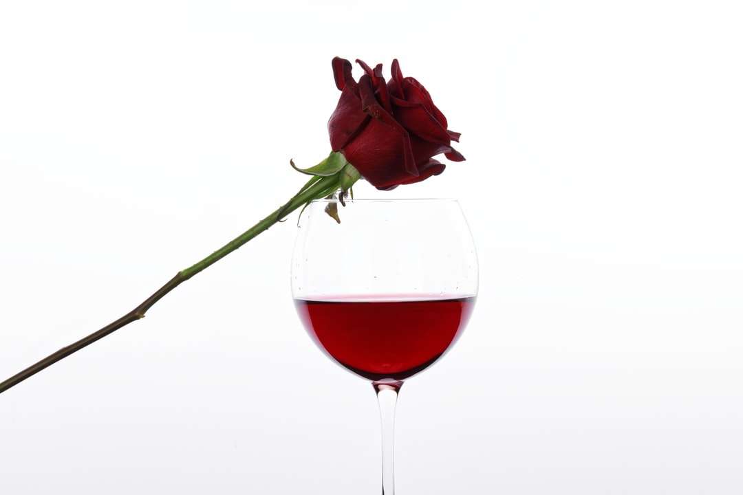 rose rouge dans un verre à vin clair puzzle en ligne